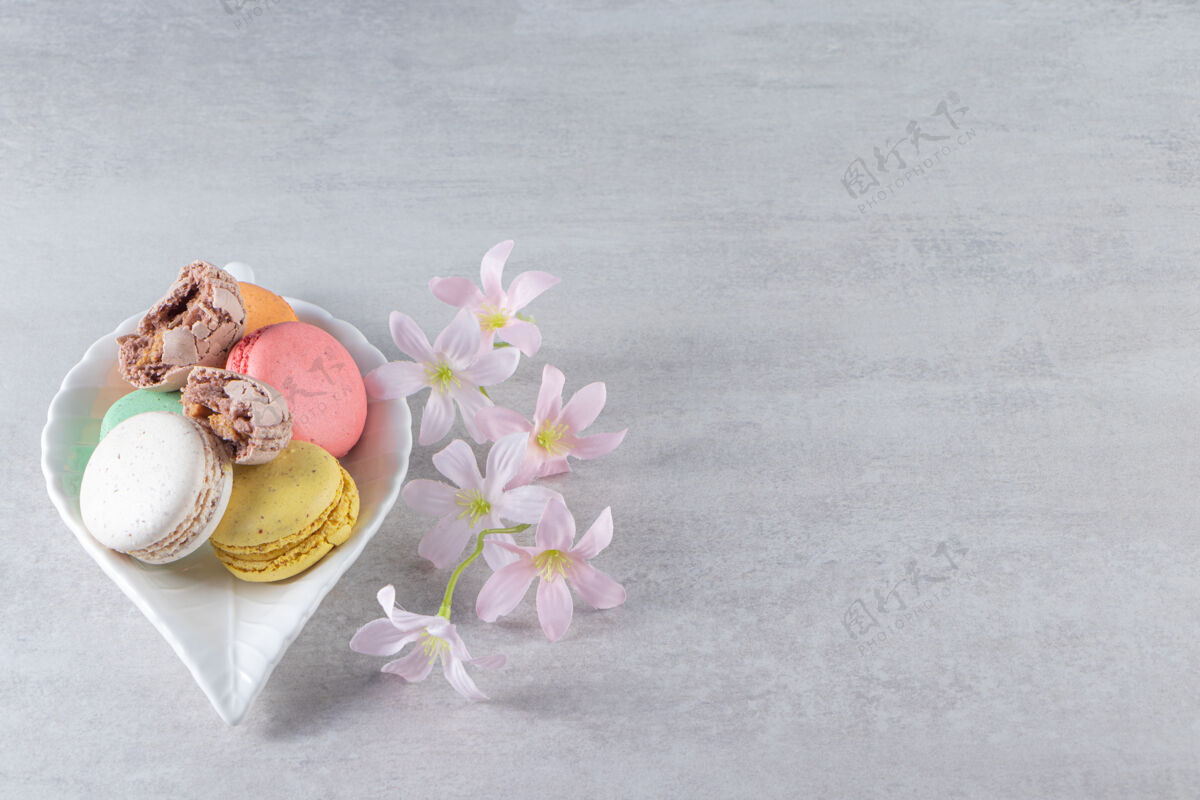 食品石头桌上摆着一盘五颜六色的带花的甜杏仁饼奶油饼干蛋糕