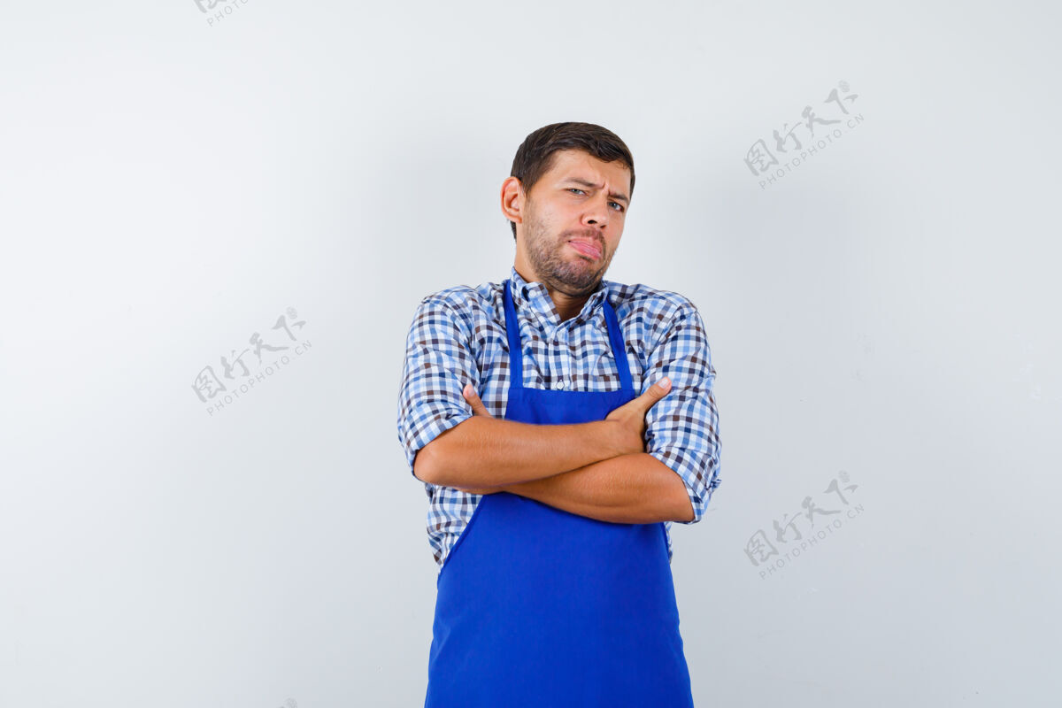 烹饪穿着蓝色围裙和衬衫的年轻男厨师年轻男士男士