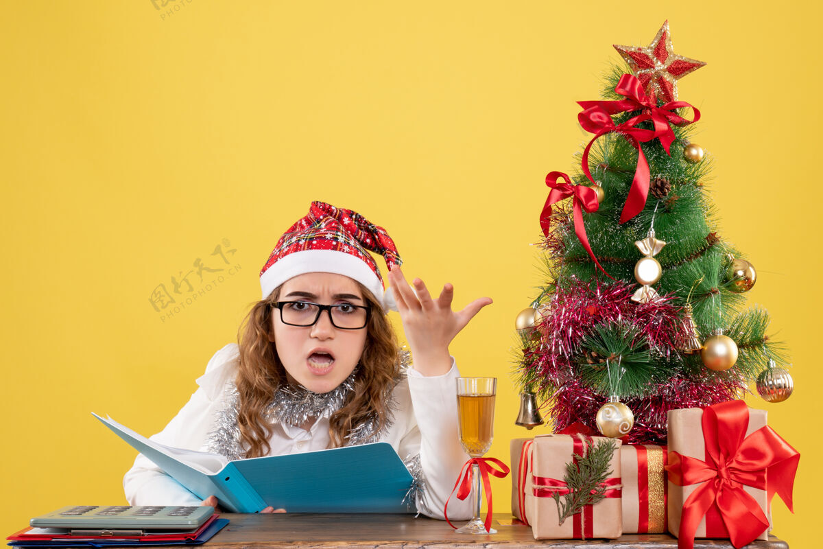 快乐前视图女医生在桌子后面看文件餐桌圣诞色彩