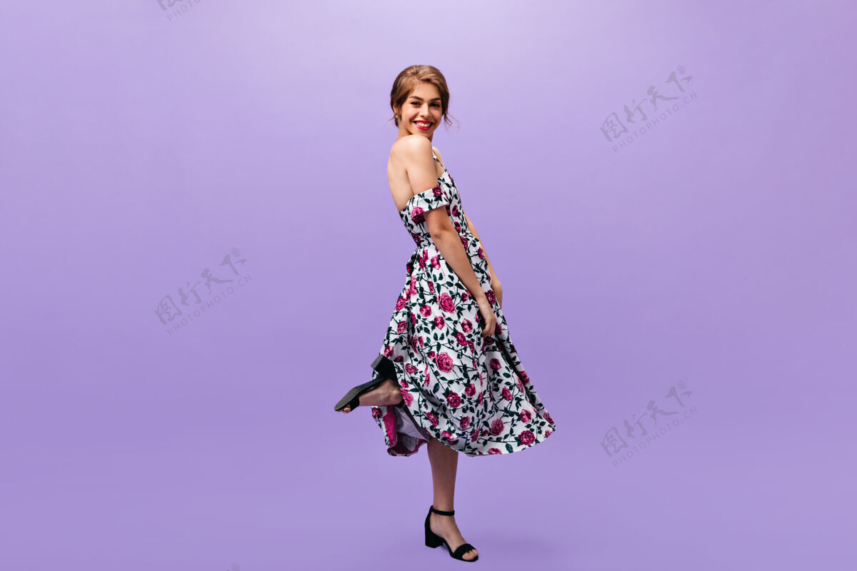 姿势害羞的女人穿着时髦的衣服在紫色的背景上摆姿势穿着五颜六色的现代服装的漂亮时髦的女人对着镜头微笑紫色头发表情