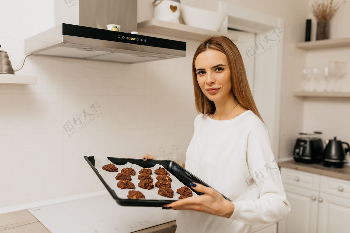 阅读一个年轻的女人学着做饭 手里拿着自制的饼干微笑人失落