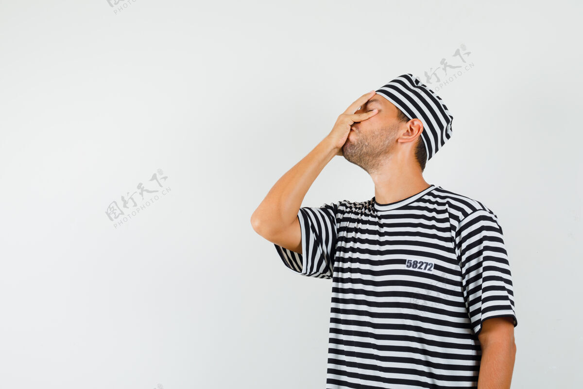 人年轻的男人手拉着脸 戴着条纹t恤帽子 看起来健忘虚拟抱着接听电话