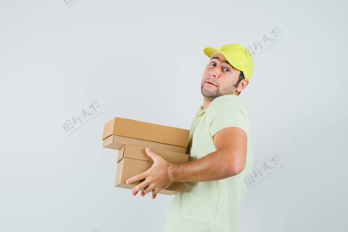 自信戴着t恤帽的年轻人手里拿着沉重的纸板箱帽子盒子休闲