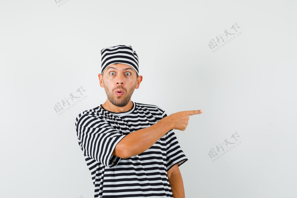 男一个戴着条纹t恤帽子的年轻人指着侧面 看上去很害怕指男条纹