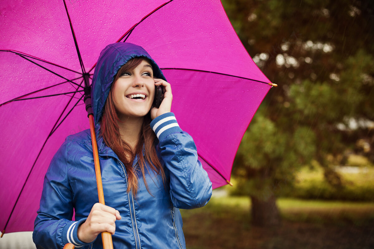 护理雨天带手机的年轻女子无忧无虑天气女性