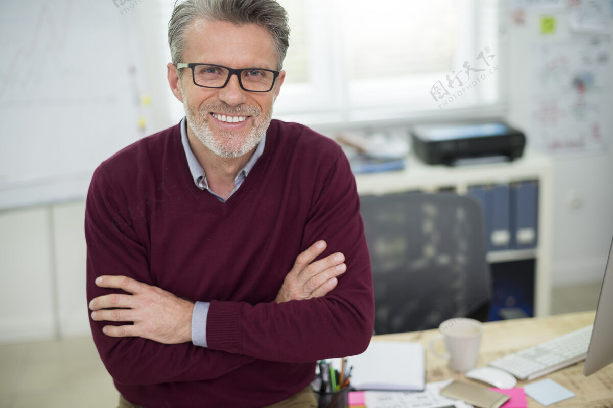 休息坐在书桌上的快乐男人的画像男人眼镜老板