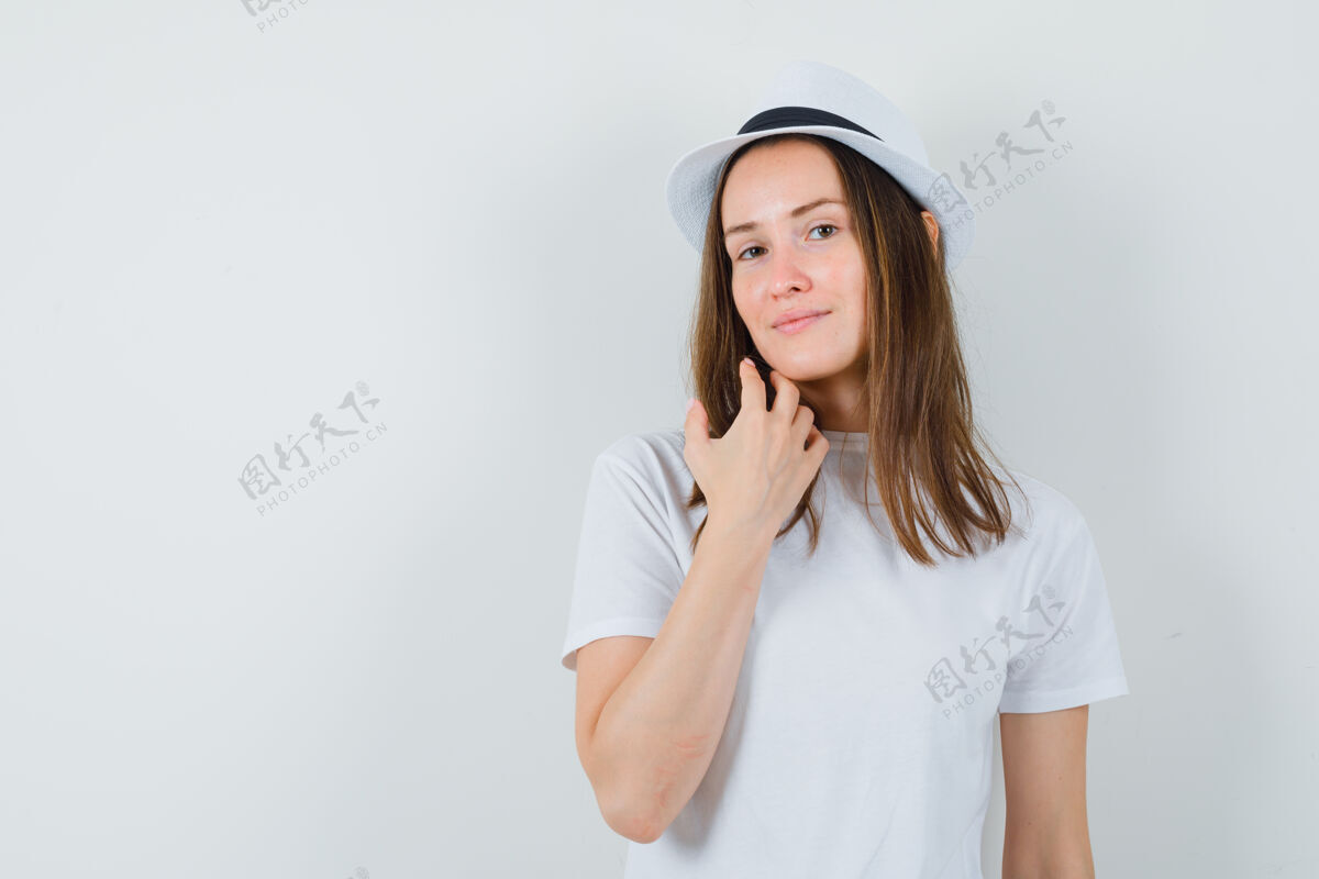 一起戴着白色t恤帽子的年轻女士抚摸着下巴 看起来很漂亮连衣裙人性化触摸