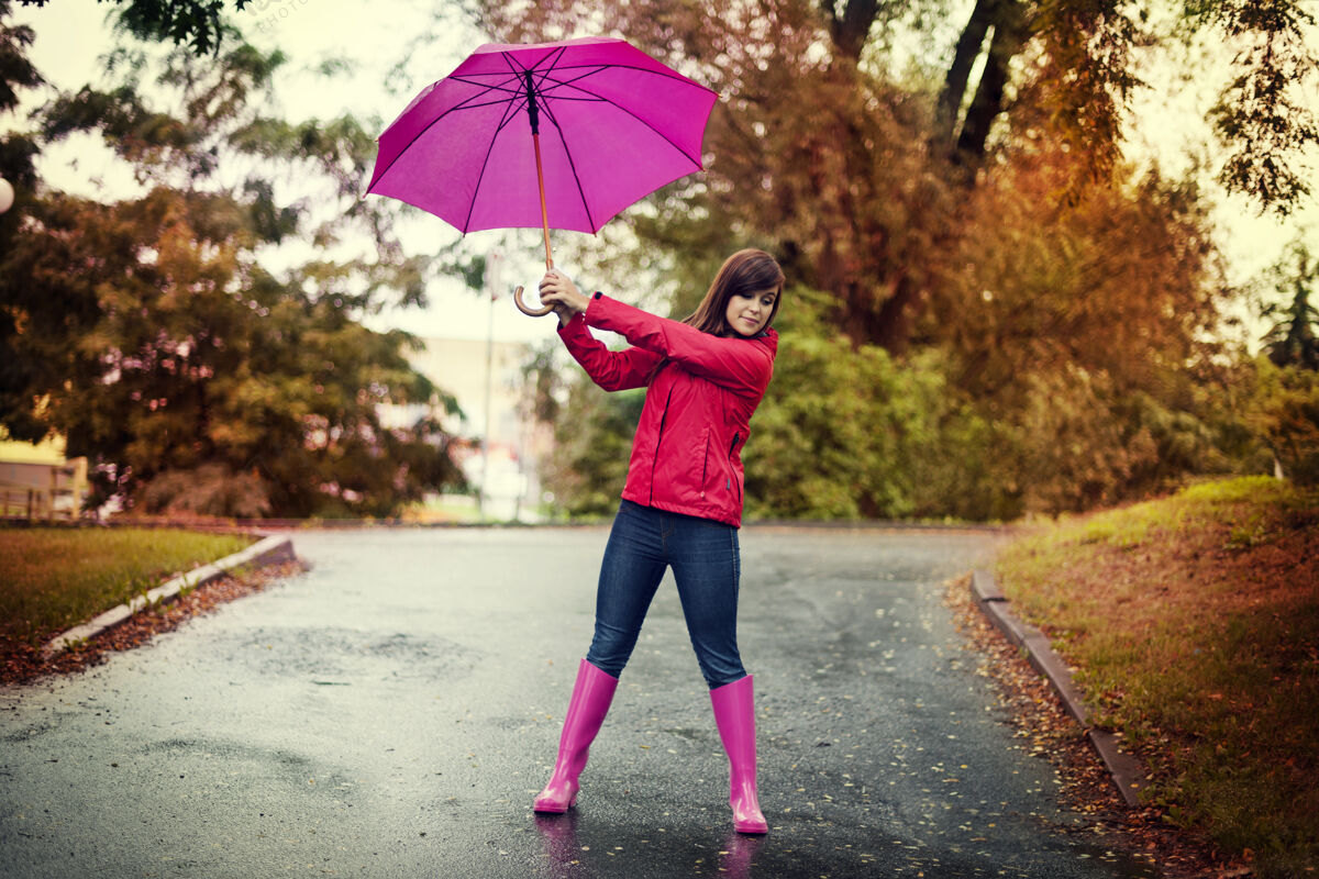 可爱公园里拿着粉红色伞的年轻女子女性肖像无忧无虑