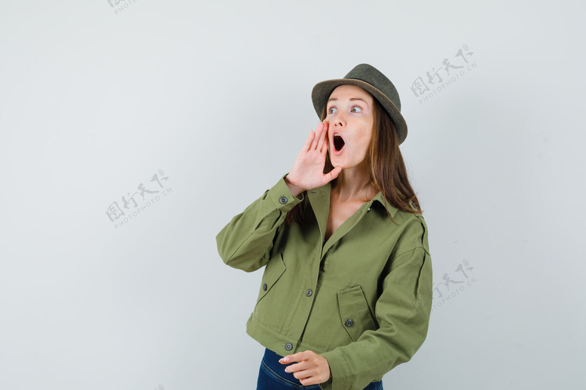拿着一位年轻的女士手拉手 嘴张开 穿着夹克 戴着裤子和帽子 看上去很惊讶裤子一起开