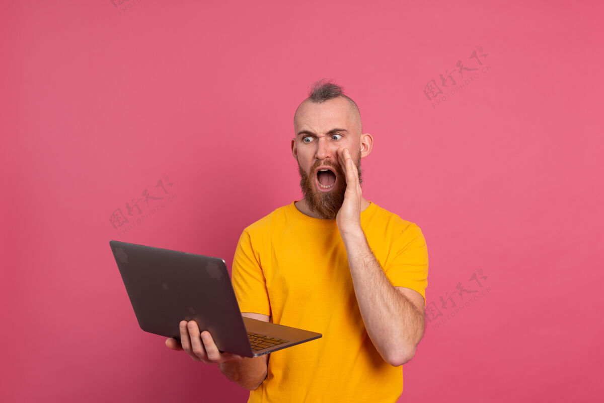 人一个留着胡子的男人 带着笔记本电脑 在粉色背景上尖叫着男胡子站