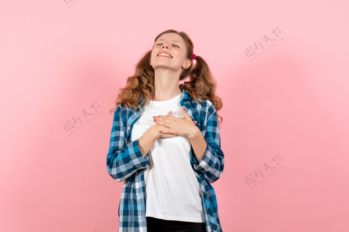 成人正面图身着格子衬衫的年轻女性在粉色背景上摆姿势年轻女性彩色情感模特儿肖像微笑漂亮