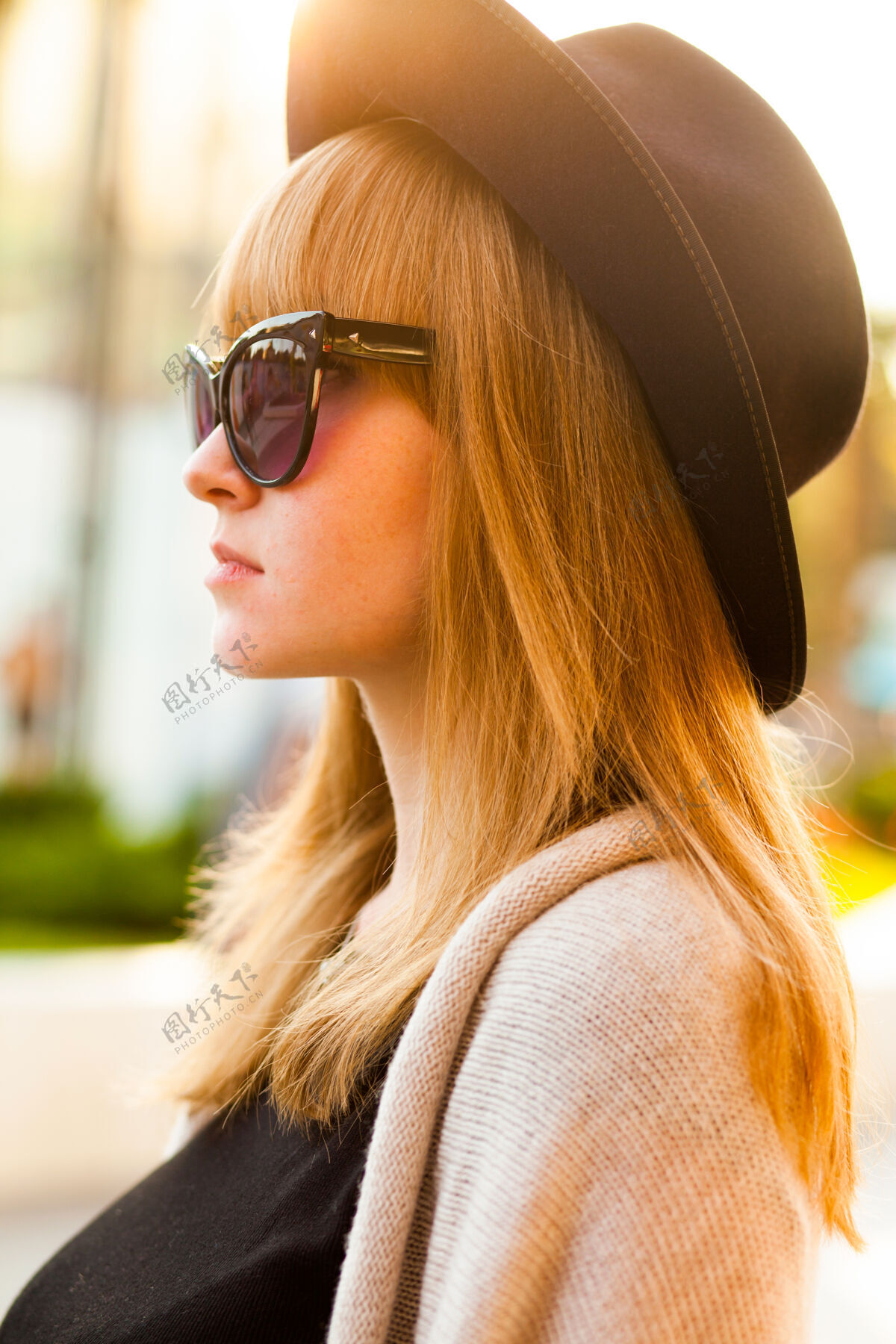 梦想时尚写真的年轻潮人女子戴着帽子和太阳镜在日落时分的沙滩上 复古风格的色彩色调寒冷的季节温暖的衣服户外优雅女人
