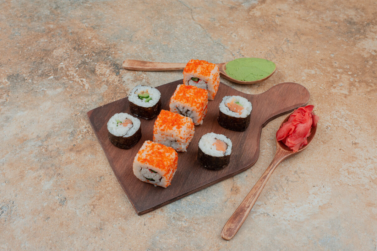 汤匙美味的寿司 鱼子酱 姜和瓦萨比放在木盘上米饭鱼食物