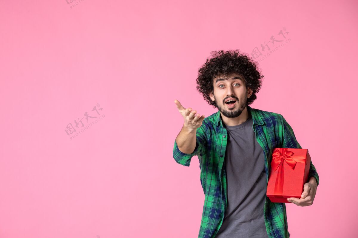 肖像浅粉色墙上红色包裹的年轻男性正面图粉色人盒子