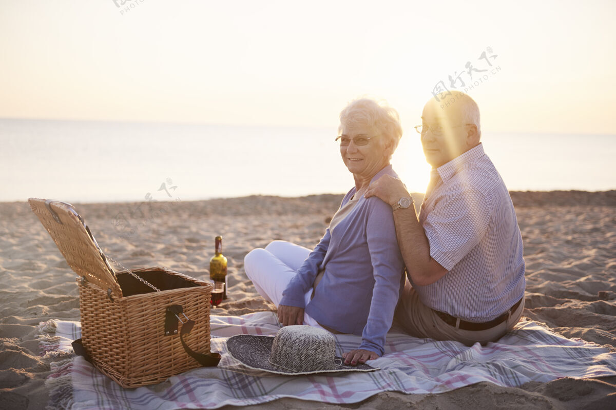 衰老过程日落时在海滩上野餐人际关系团聚浪漫