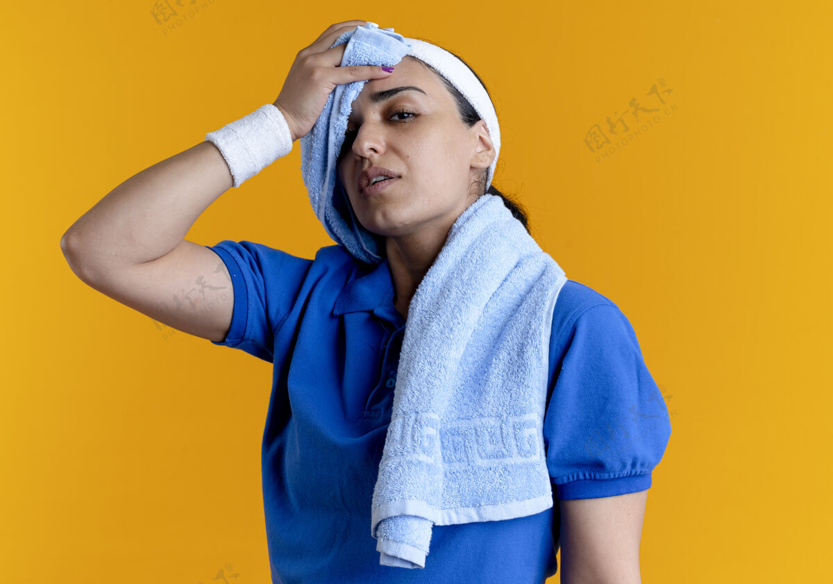 信心年轻自信的白人运动女性戴着头带和腕带 脖子上戴着毛巾 用橘黄色的毛巾擦拭额头 留有复印空间女士毛巾太空