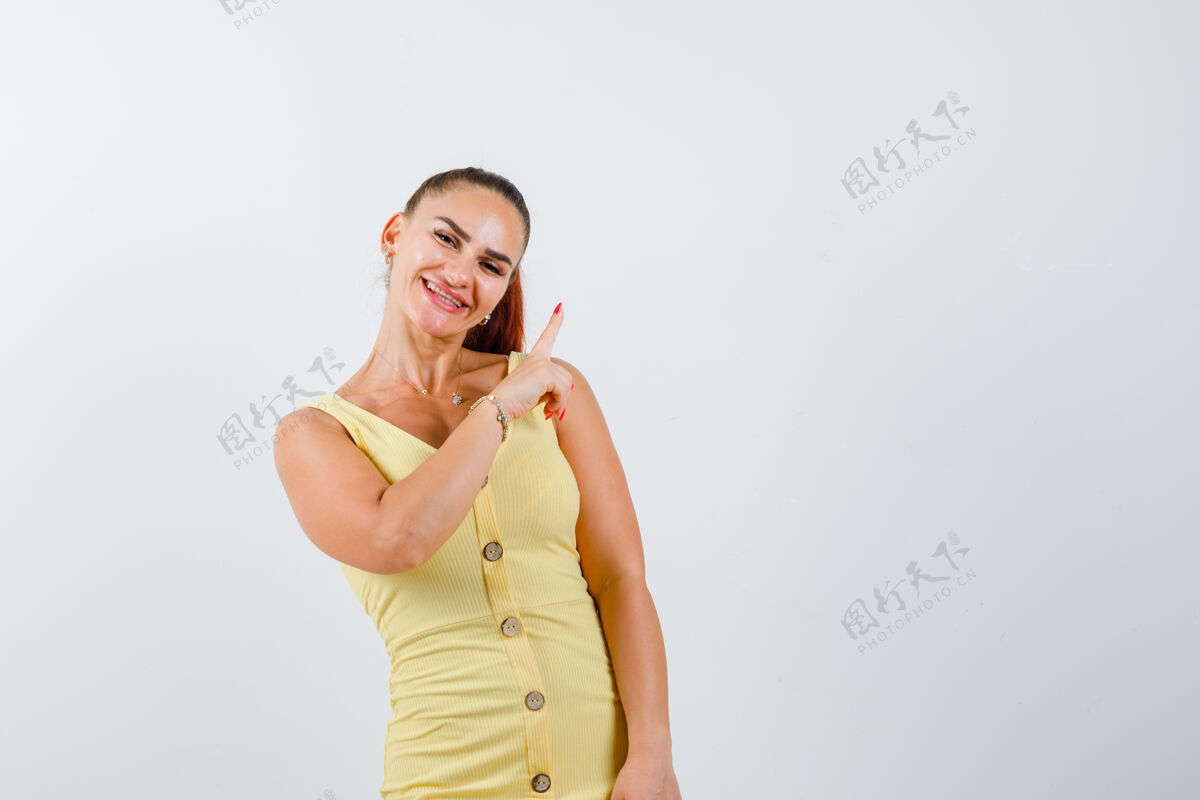 女人年轻漂亮的女性的肖像指着右上角的裙子 看着快乐的前景色房子礼物微笑