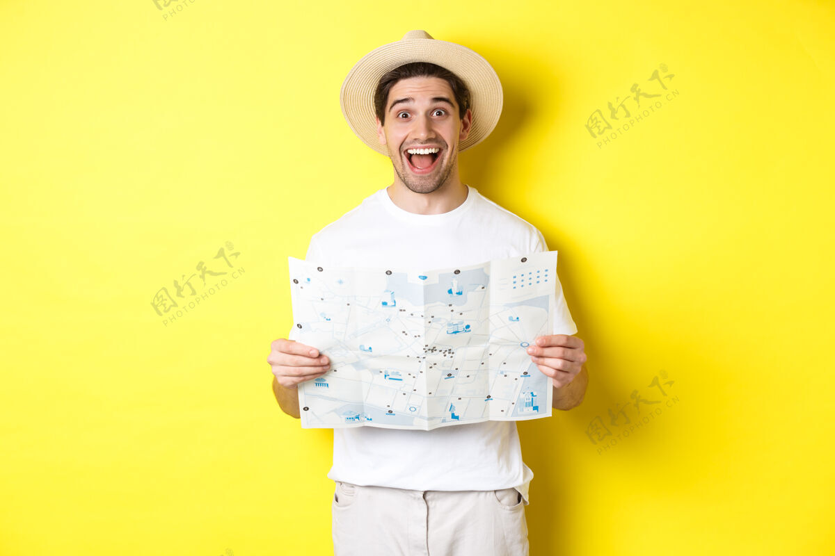 地图旅游 度假和旅游概念兴奋的男子旅游观光与地图 站在黄色背景假日帽子表情