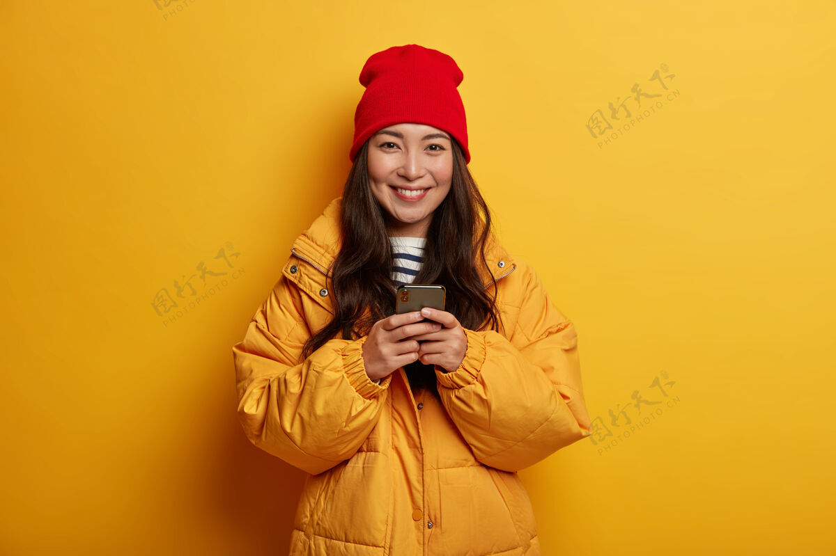 姿势年轻漂亮的女人拿着圣诞装饰品夹克手机通知