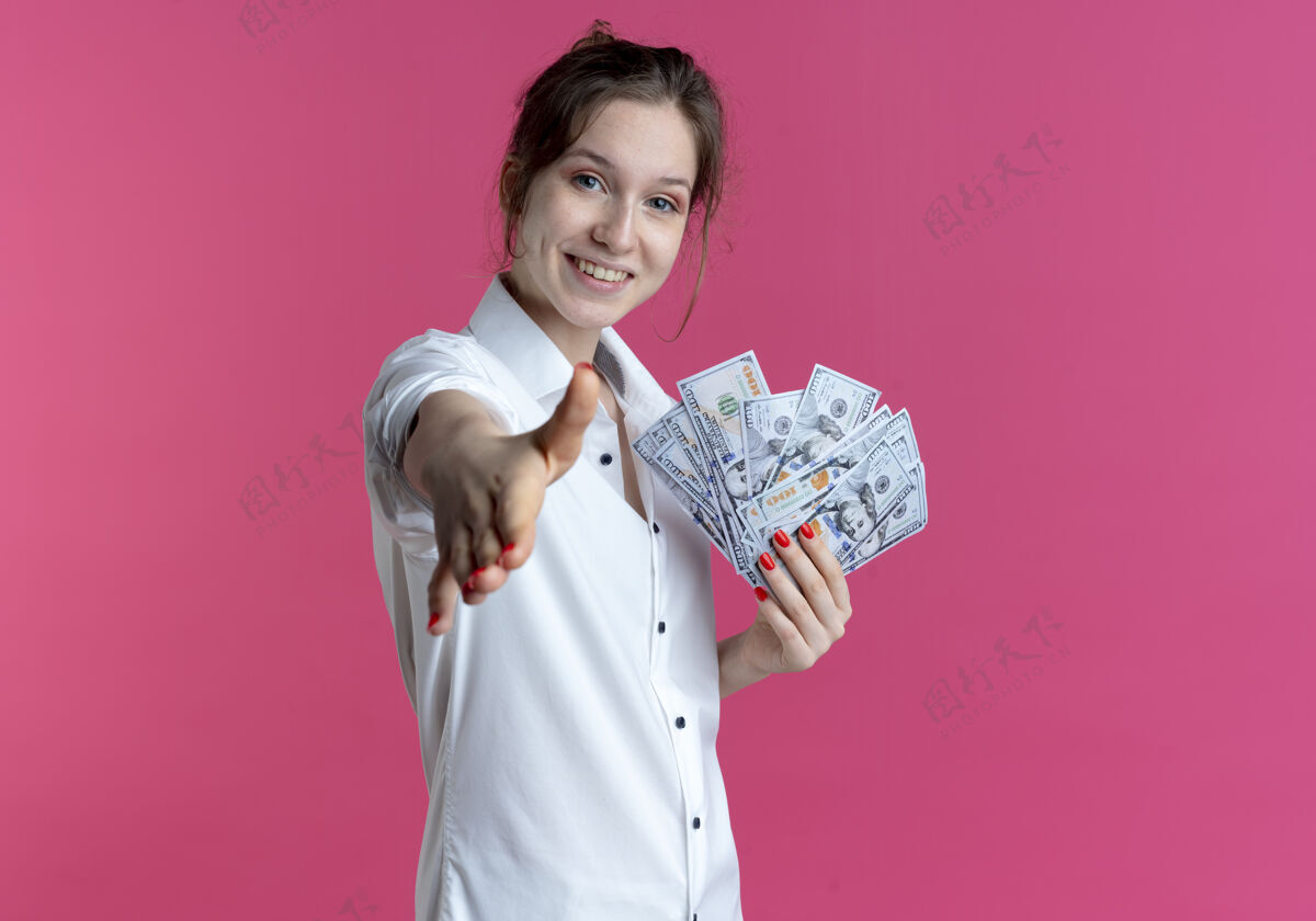 钱年轻的微笑的金发俄罗斯女孩伸出手拿着粉红色的钞票和复印空间女孩金发年轻