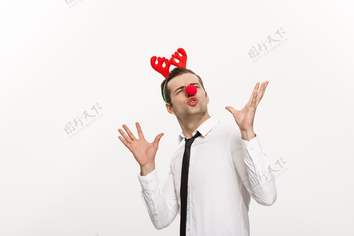 圣诞节帅气的商人戴着驯鹿发带做着滑稽的表情隔离在白色上手势商人男性