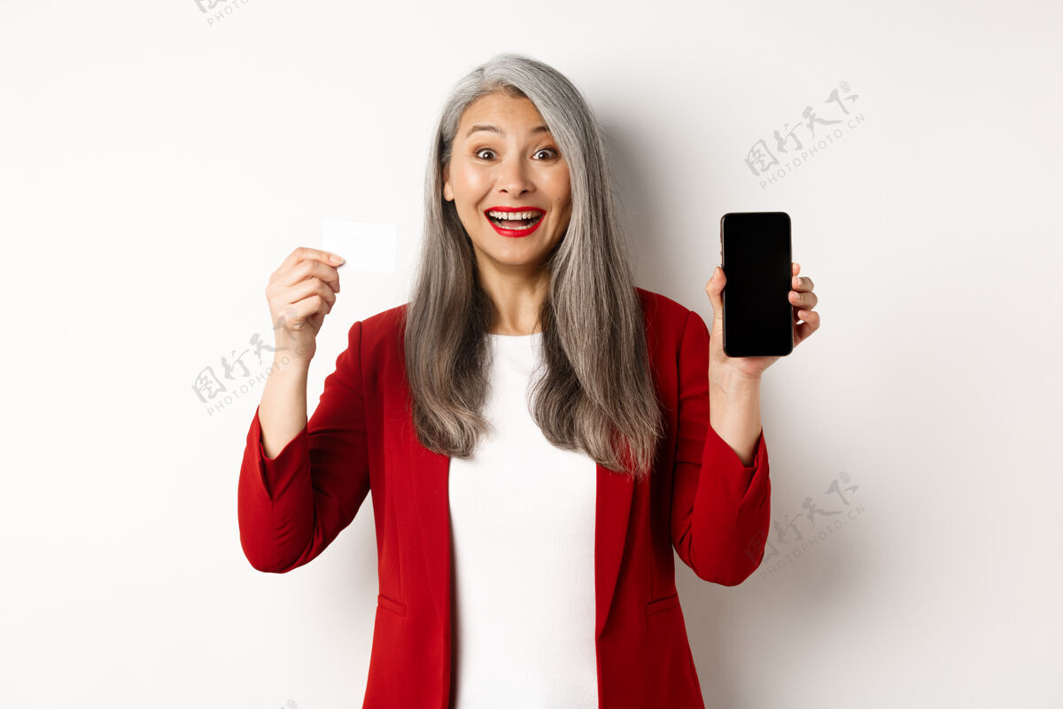 工人开朗的亚洲成熟女性展示空白的智能手机屏幕和信用卡 电子商务的概念秀手机个人