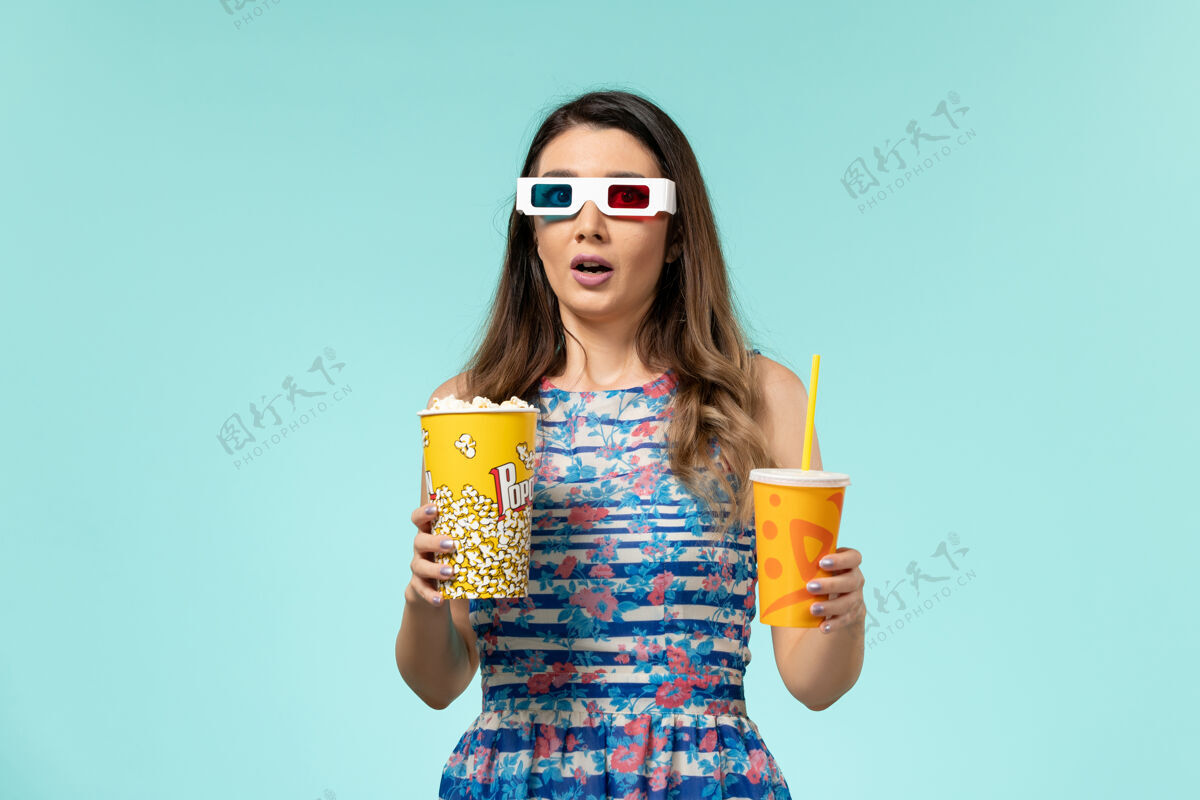 电影院前视图年轻女性手持爆米花饮料在d太阳镜浅蓝色表面电影院手捧性感