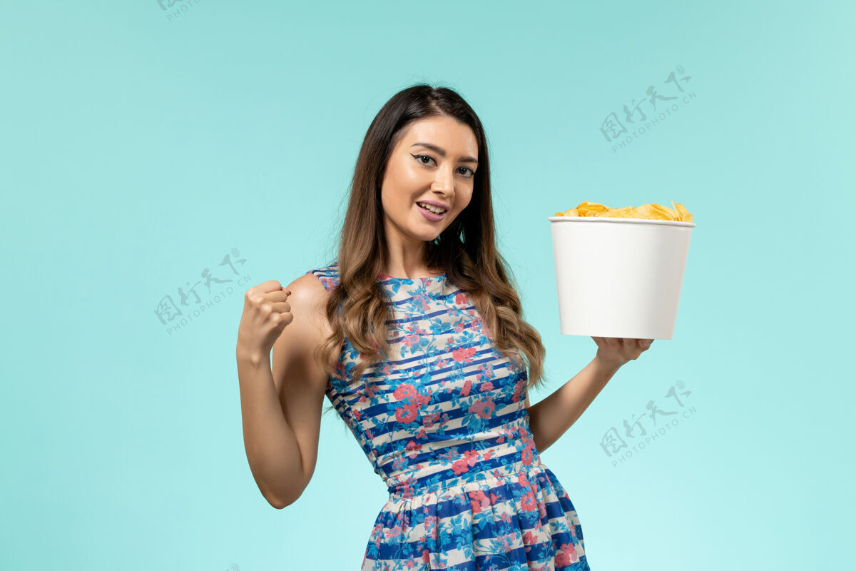 篮子正面图：年轻的女性拿着篮子 蓝色桌子上放着薯片电影性感土豆