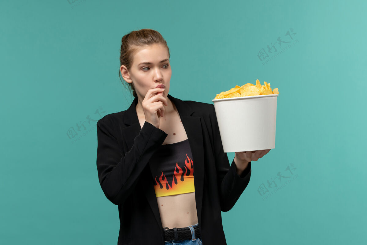 西装正面图：年轻女性在淡蓝色的表面上吃薯片看电影企业家电影女性