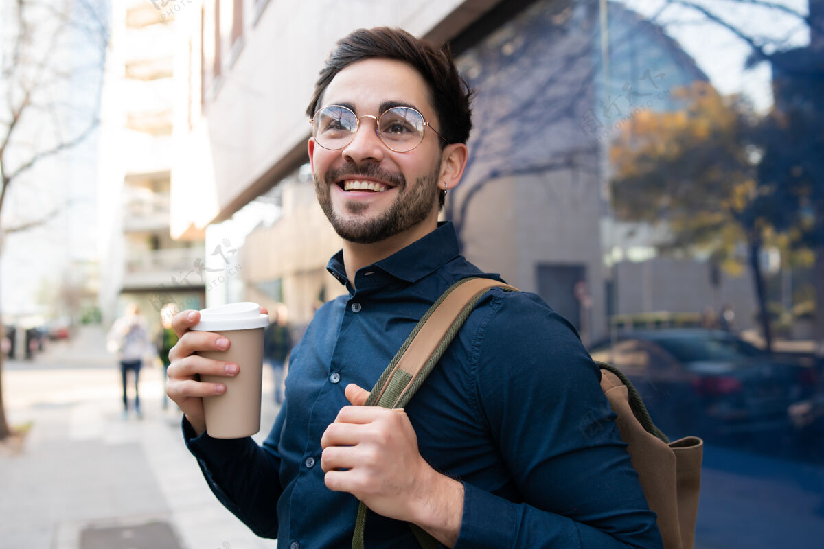 男人年轻人拿着一杯咖啡在街上走在户外的肖像城市和生活方式的概念户外自信休闲
