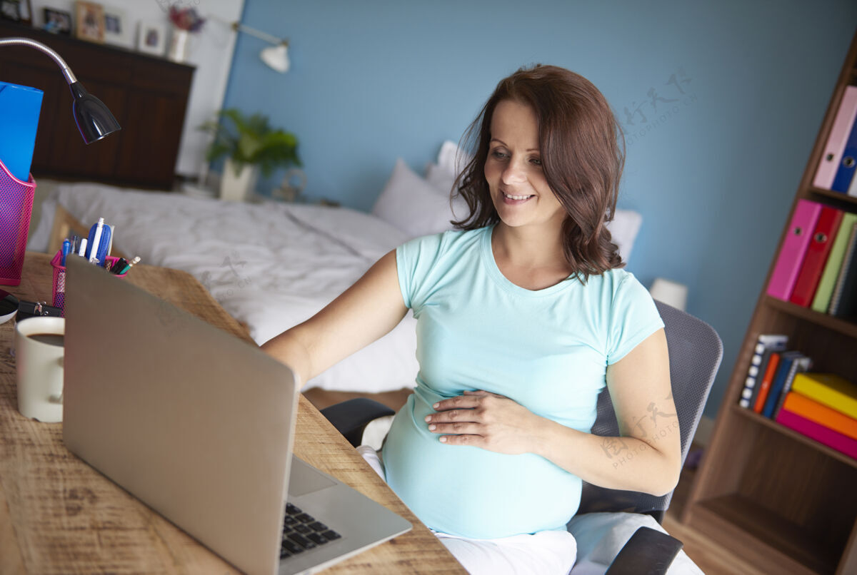 笑脸孕妇在家使用电脑人的腹部在家工作怀孕
