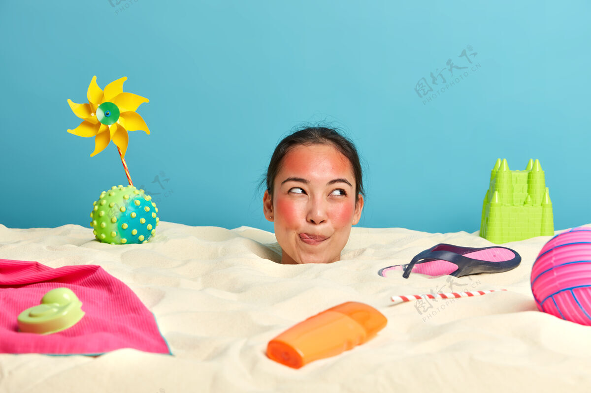 人年轻女子头上涂着防晒霜 脸上围着沙滩饰品阳光满意舔
