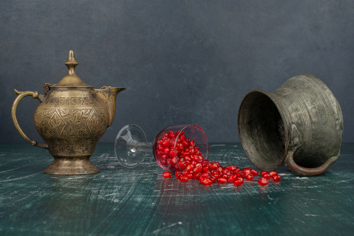 种子石榴籽撒在大理石桌上 还有花瓶和茶壶成熟红色花瓶