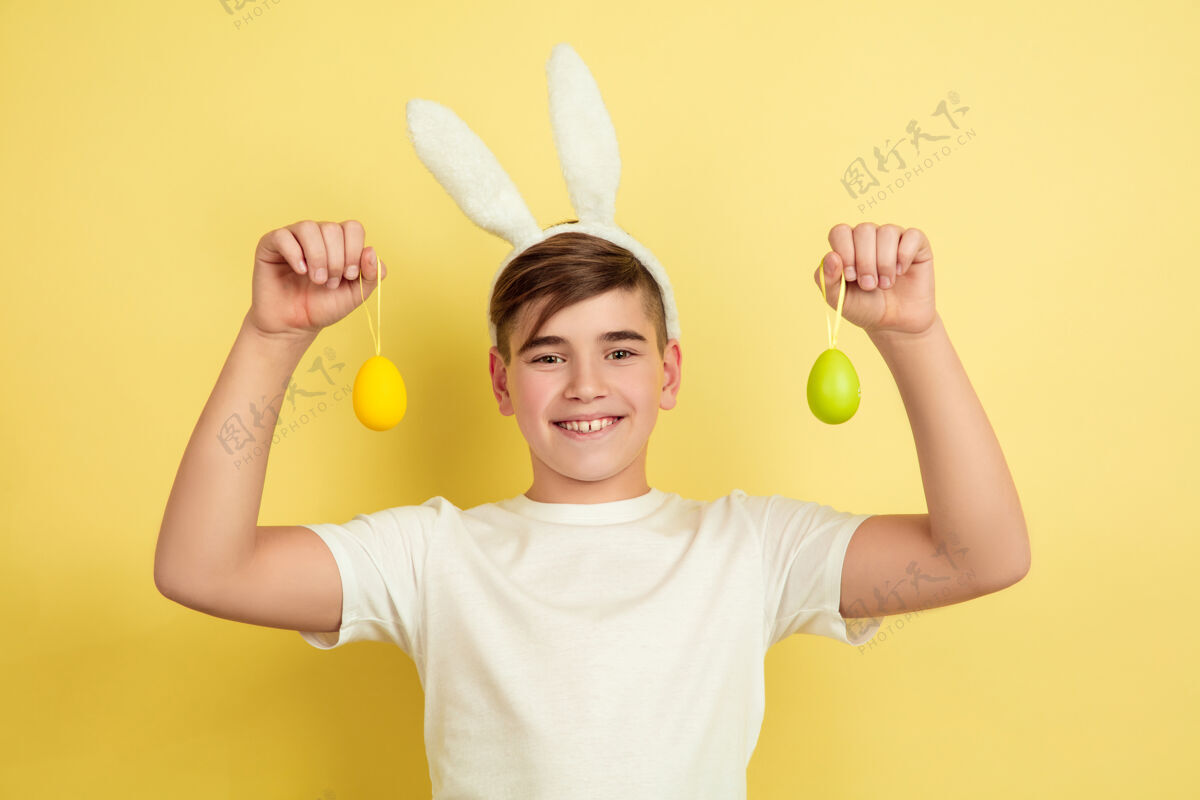 鸡蛋男孩像复活节兔子在黄色的工作室墙上光明有趣肖像