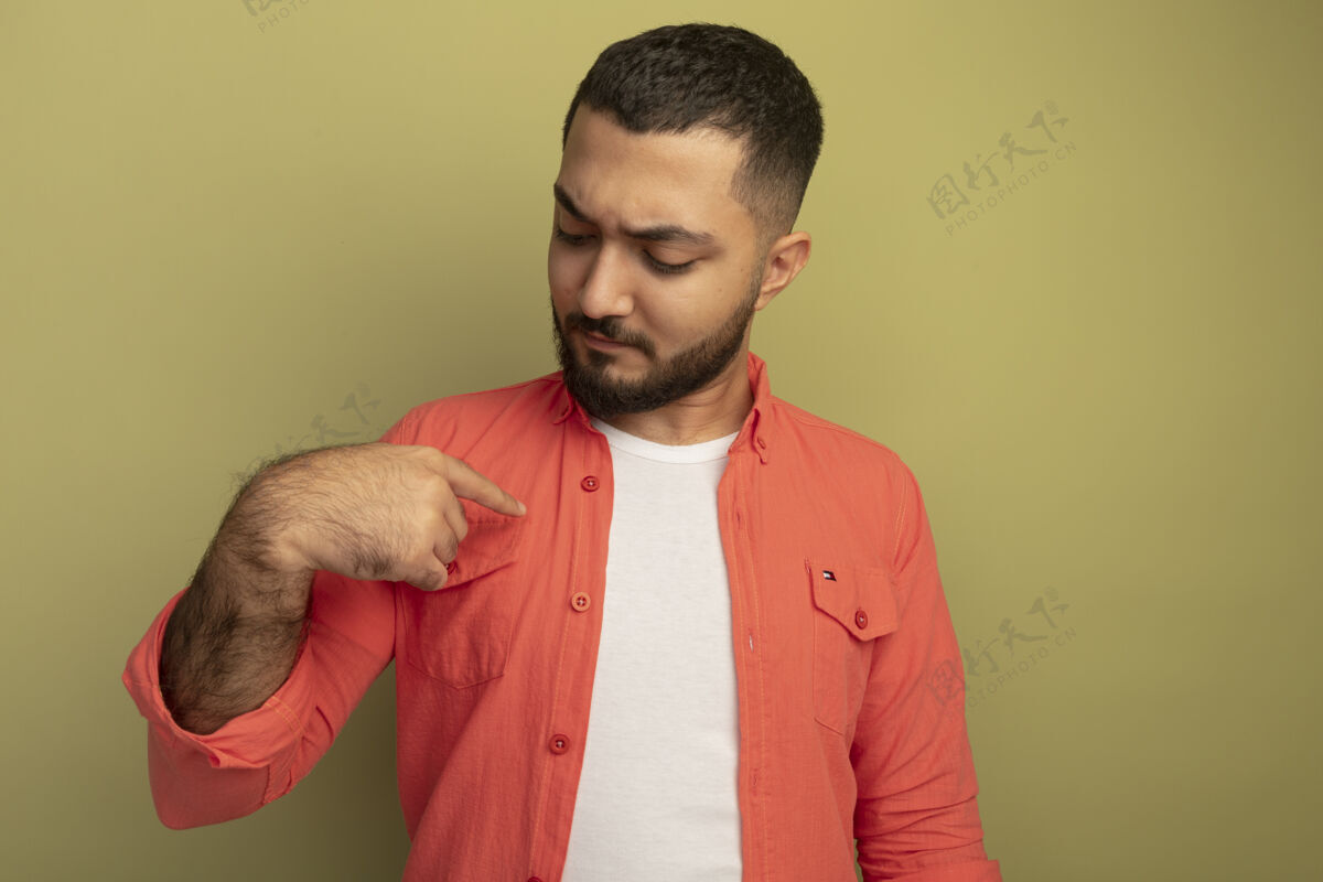 光一个穿着橘色衬衫 留着胡子的严肃的年轻人用手指着站在光墙上的自己手指严肃指着