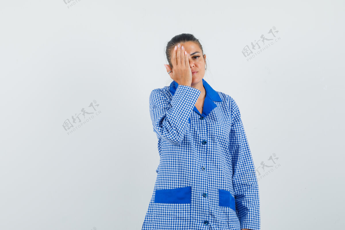 眼睛年轻女子试图用手遮住眼睛在蓝色方格睡衣衬衫 看起来很严肃 正面视图试试健康自然