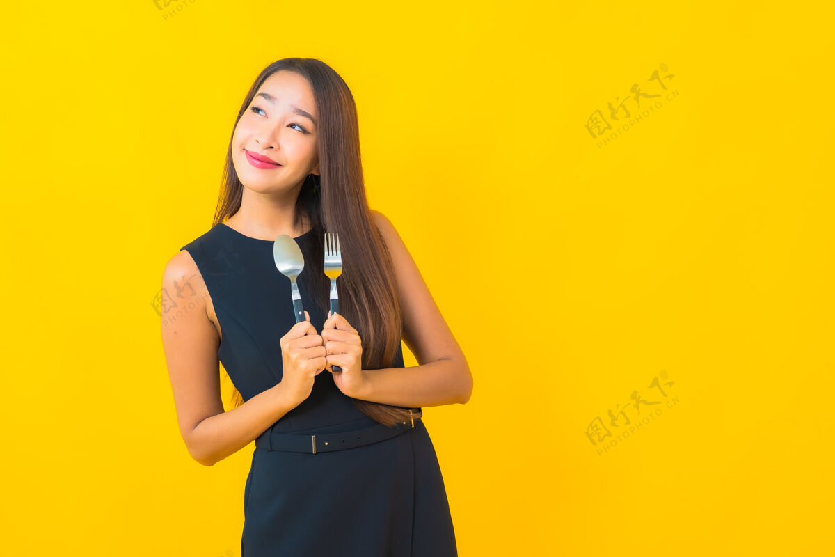 女孩肖像美丽的亚洲年轻女子准备用叉子和勺子吃黄色背景餐具人早午餐