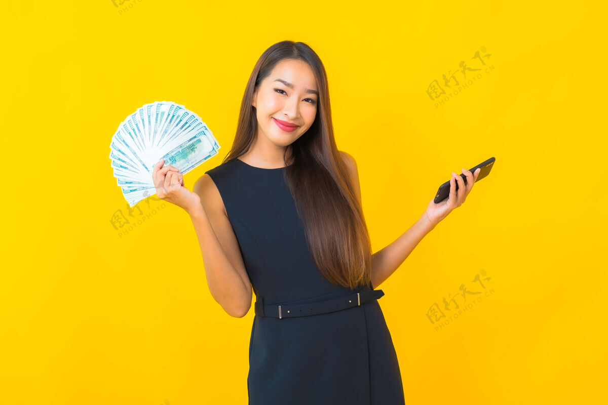 帐单在黄色背景上描绘一个年轻漂亮的亚洲女商人 她有很多现金和金钱财务工资微笑