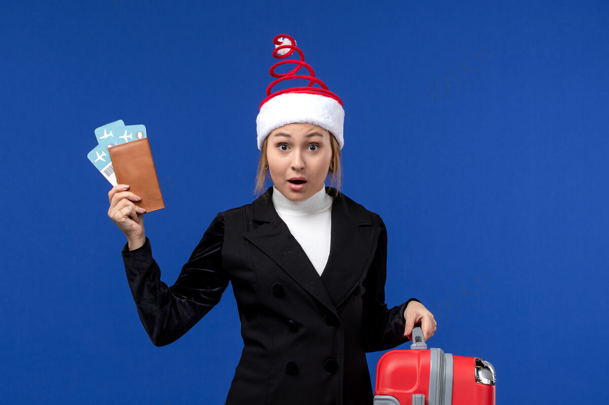 飞机前视图年轻女性拿着机票和包在蓝色背景度假飞机度假包前面西装