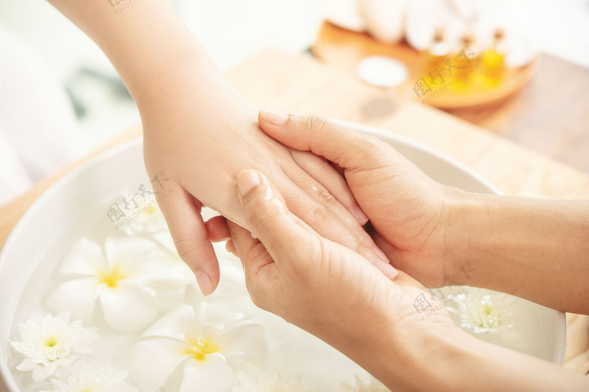 芳香疗法美容师按摩手的女性水疗沙龙客户水疗治疗和产品的女性脚和手水疗健康手指碗