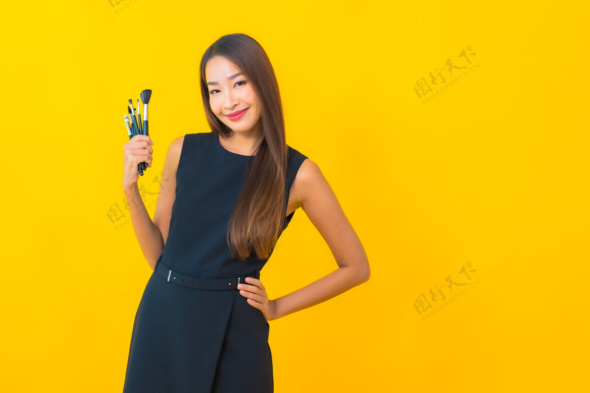 在线在黄色背景上用化妆刷描绘美丽的亚洲女商人设备博客现场