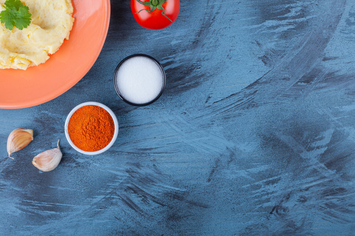 番茄把土豆泥放在盘子里 放在蔬菜和香料碗旁边 放在蓝色的桌子上营养土豆纯的