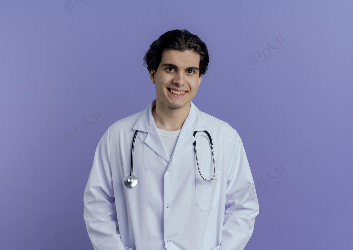 站面带微笑的年轻男医生穿着医用长袍和听诊器 站在紫色的墙壁上 隔离着复印空间男性医疗听诊器