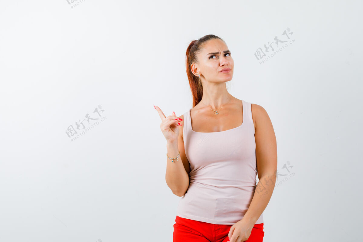 人年轻女孩举起食指在尤里卡手势在米色上衣和红色裤子 看起来理智 前视图模特尤里卡愉悦