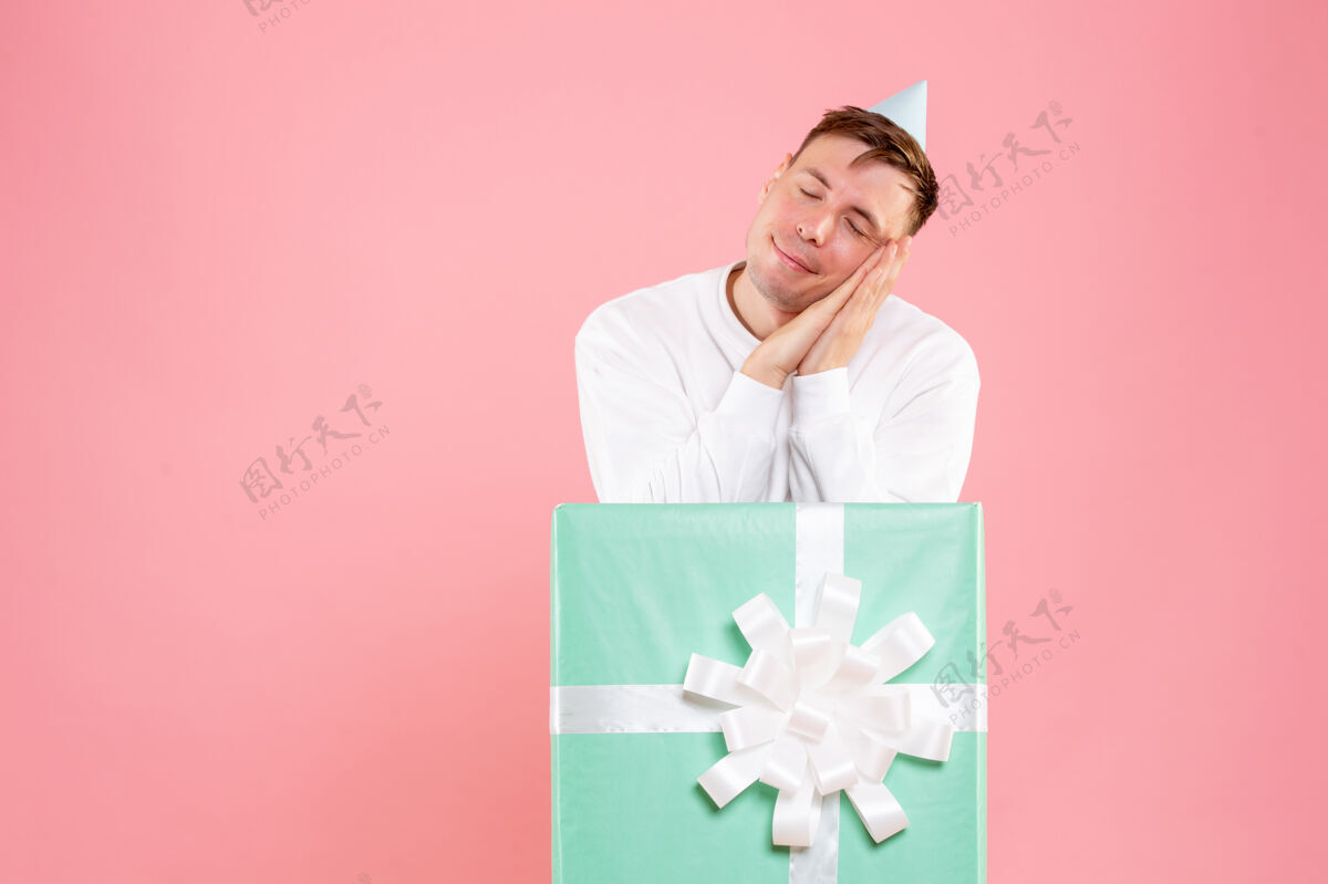 圣诞正面图年轻男性在粉色背景下假装睡觉睡眠年轻男性假装