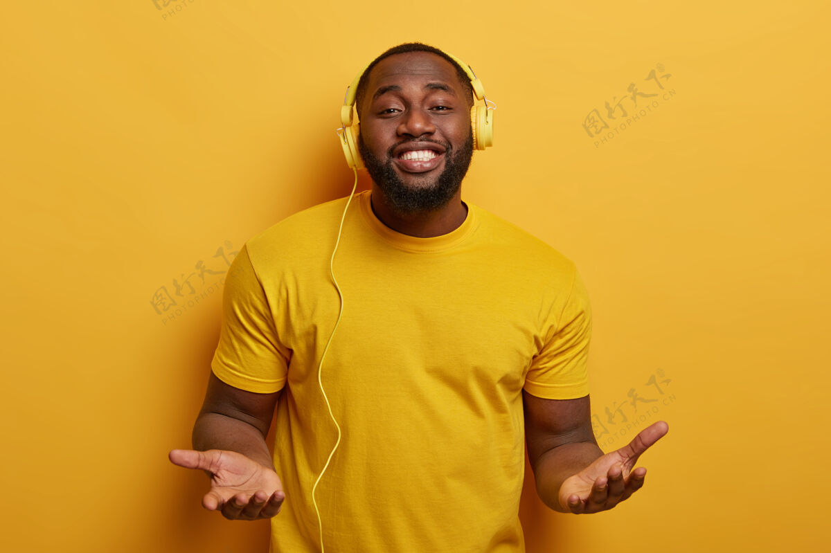 放松帅气丰满的黑皮肤男人 有着完美的心情和酷酷的音乐 戴着耳机享受着美妙的声音声音微笑表情