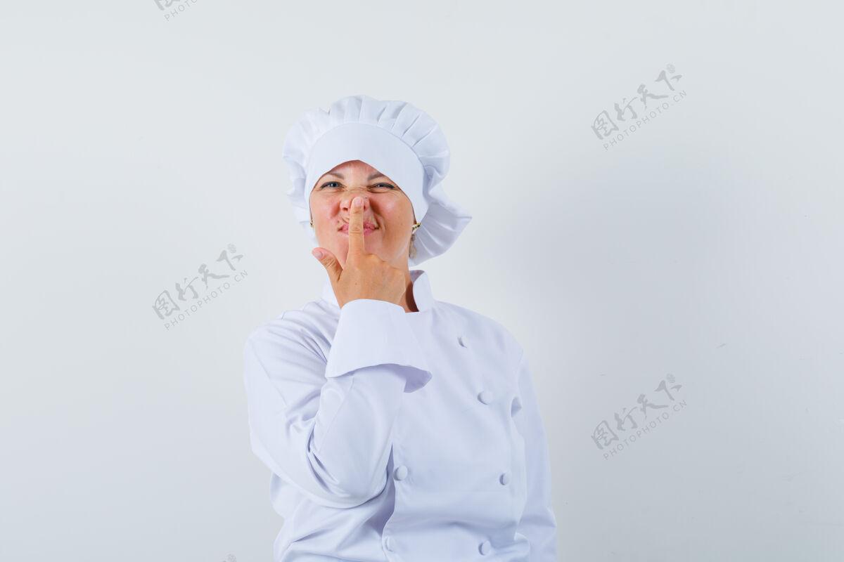 欢呼穿白色制服的女厨师用手指抚摸鼻子 看起来很可爱女士表情学生