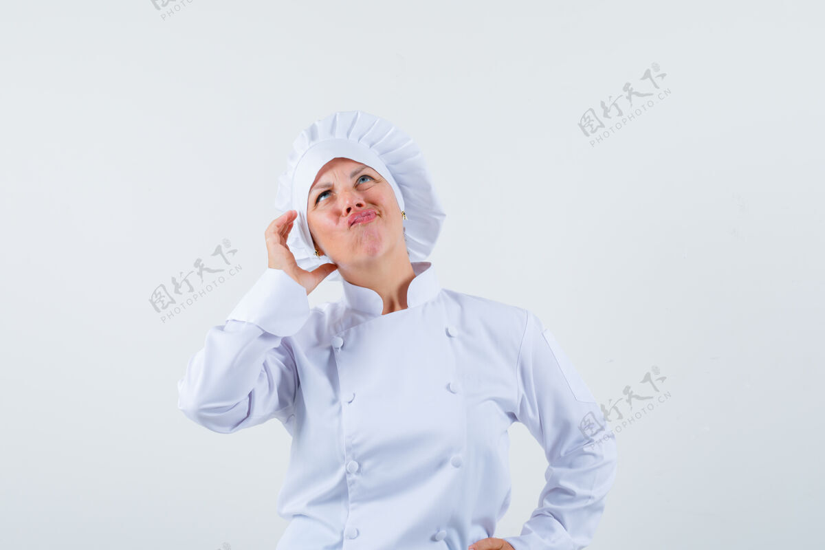 魅力女厨师摆出像在打电话一样的姿势 穿着白色制服思考 看起来很专注而嘴唇电话