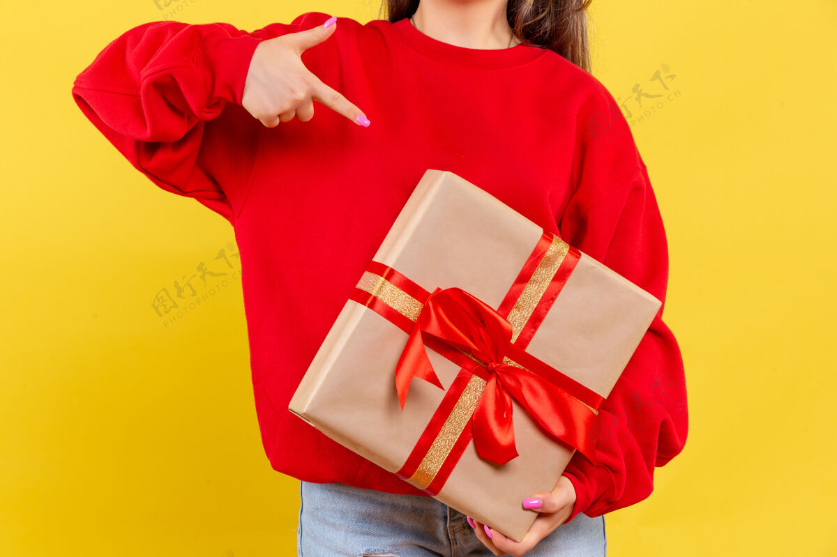风景前视图年轻女子手持圣诞礼物黄色背景圣诞节衣服成人