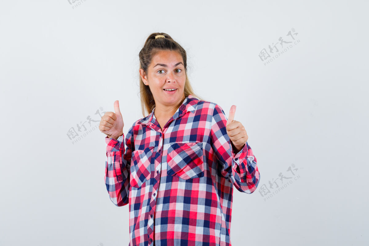 前面照片中的年轻女士穿着格子衬衫 向上竖起大拇指 看上去很快乐双人床成人脸